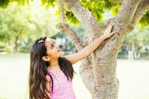 a young girl is reaching up to a tree photo