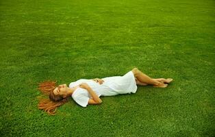 a woman laying on the grass in a white dress photo