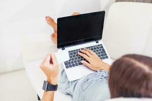 a woman sitting on a couch with her laptop photo