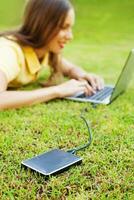 woman using hard drive disk to backup her data while lying down relaxed on a grass photo