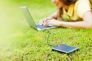 woman using hard drive disk to backup her data while lying down relaxed on a grass photo