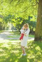 a woman holding a baby in a park photo