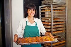 a woman holding a tray of baked goods photo