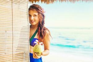 a woman in a bikini holding a coconut photo