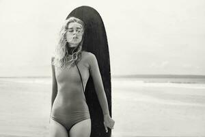 un mujer en un traje de baño participación un tabla de surf foto