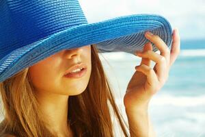 a woman wearing a blue hat on the beach photo