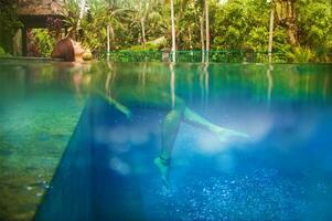 a woman is floating in a pool with a tree in the background photo