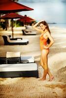 a woman in a orange swimsuit standing on a beach photo