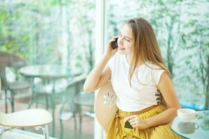 un mujer sentado a un mesa hablando en un célula teléfono foto