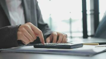 Asian Business woman using calculator and laptop for doing math finance on an office desk, tax, report, accounting, statistics, and analytical research concept video