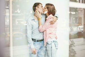 young couple kissing in front of window photo