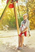 a woman sitting on a swing with her baby photo