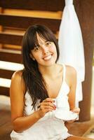 a woman sitting on a bench holding a cup of coffee photo