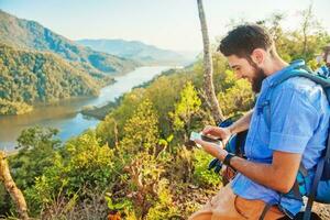 man using smartphone while hiking in the mountains photo