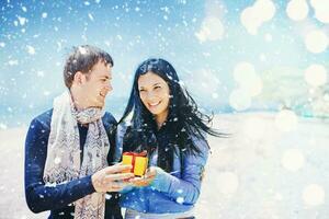 a man and woman holding a gift box on the beach photo