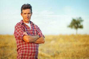 a man standing in a field with his arms crossed photo