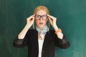 a woman in a suit and glasses is holding up her hands photo