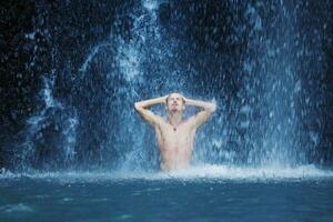 un hombre en pie en frente de un cascada foto