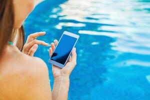template for a smart phone app woman using her phone while sitting at poolside photo