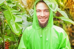 a man wearing a green raincoat in the jungle photo