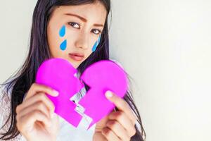 Asian woman holding a broken heart with tears on it photo