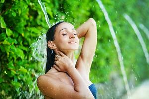 a woman in a bikini is splashing water on her head photo