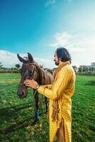 un hombre en un amarillo traje en pie siguiente a un caballo foto