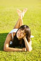 a woman laying on the grass in a park photo