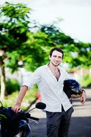 un hombre en pie siguiente a un motocicleta foto