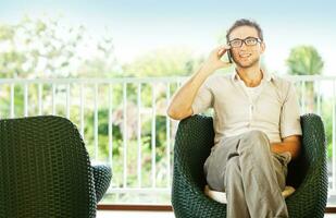 a man in glasses sitting on a chair photo