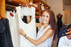a woman is holding a dress in a clothing store photo