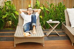 a man sitting on a chair holding a tray with a cup of coffee photo