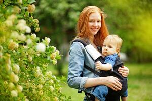 a woman holding a baby in a carrier photo