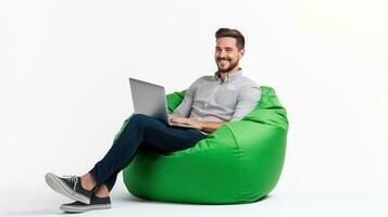 Cheerful man working on laptop seated on a green beanbag photo