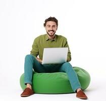 alegre hombre trabajando en ordenador portátil sentado en un verde bolsa de frijoles foto