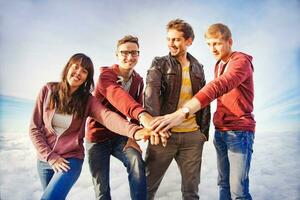 four young people standing together on a hill with their hands in the air photo