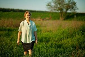 a woman is walking through a field of grass photo