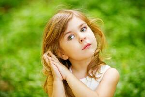 a little girl is standing in the grass with her hands on her head photo