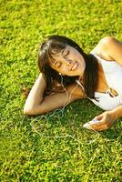 a woman laying on the grass listening to music photo