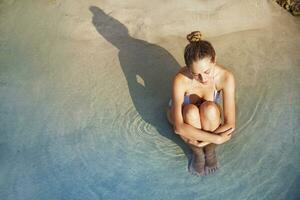 a woman sitting in the water with her legs crossed photo