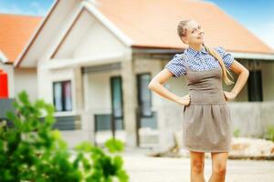 a woman in a dress standing in front of a house photo