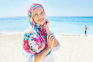 beautiful muslim caucasian russian woman wearing red dress relaxing on a beach photo