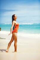 a woman in an orange swimsuit standing on the beach photo