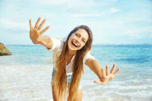 a woman is standing on the beach with her hands outstretched photo