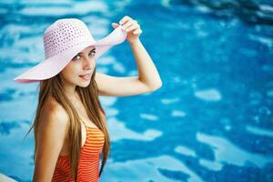 un mujer en un rosado sombrero sentado en un piscina foto