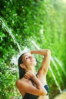 a woman in a bikini is splashing water on her head photo