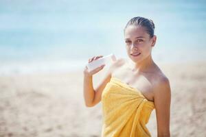 a woman in a towel holding a bottle of sunscreen photo