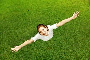 a woman is flying in the air on a green field photo