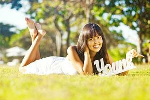 a woman laying on the grass with a sign that says you photo