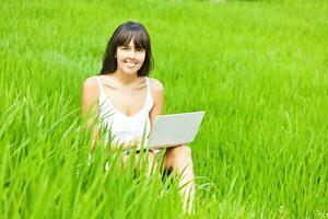 Woman with a laptop in a green field. Working remotely concept photo